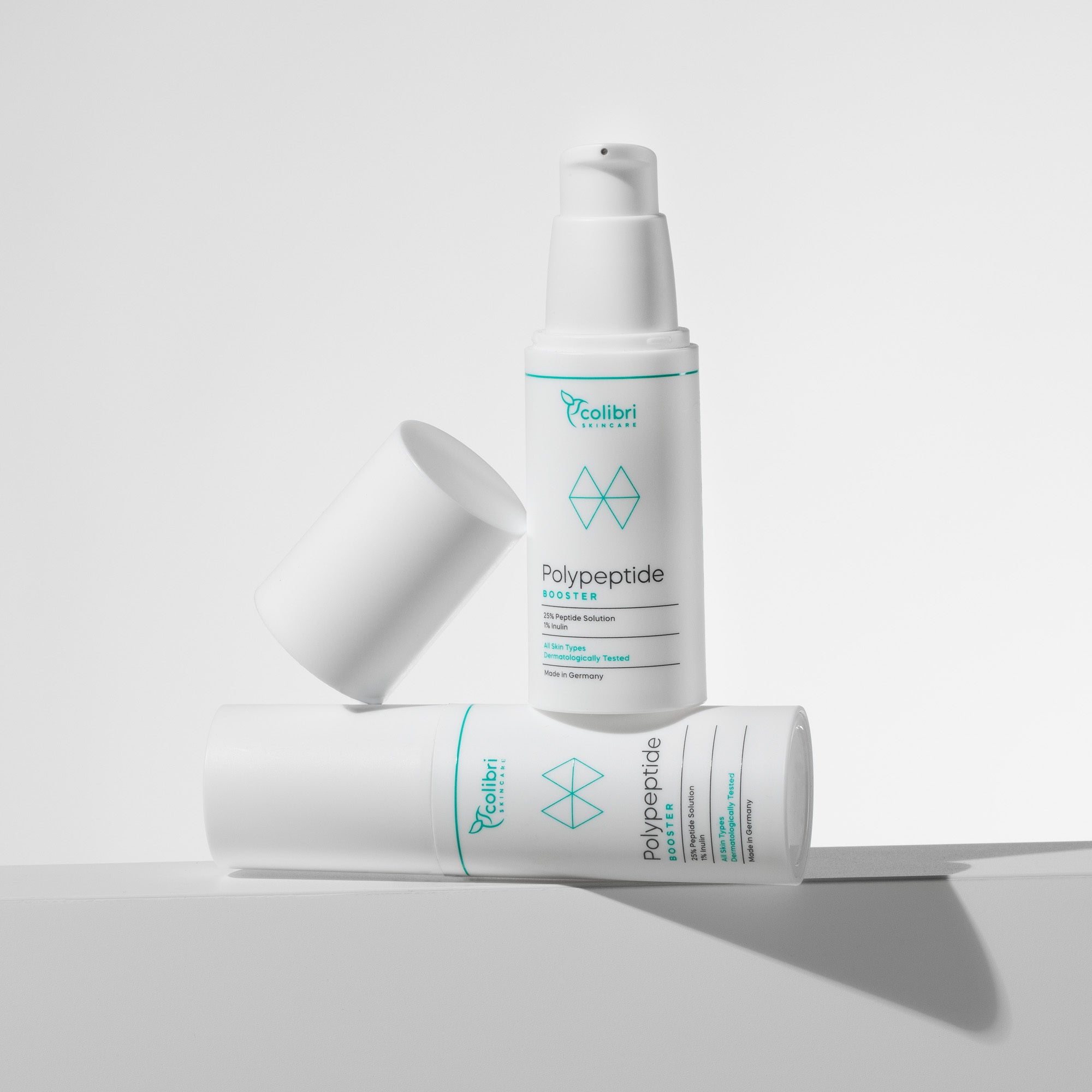 Zwei weiße Flaschen Hautpflegeprodukt mit blauem Aufdruck, eine stehend, die andere liegend, auf einem weißen Hintergrund.