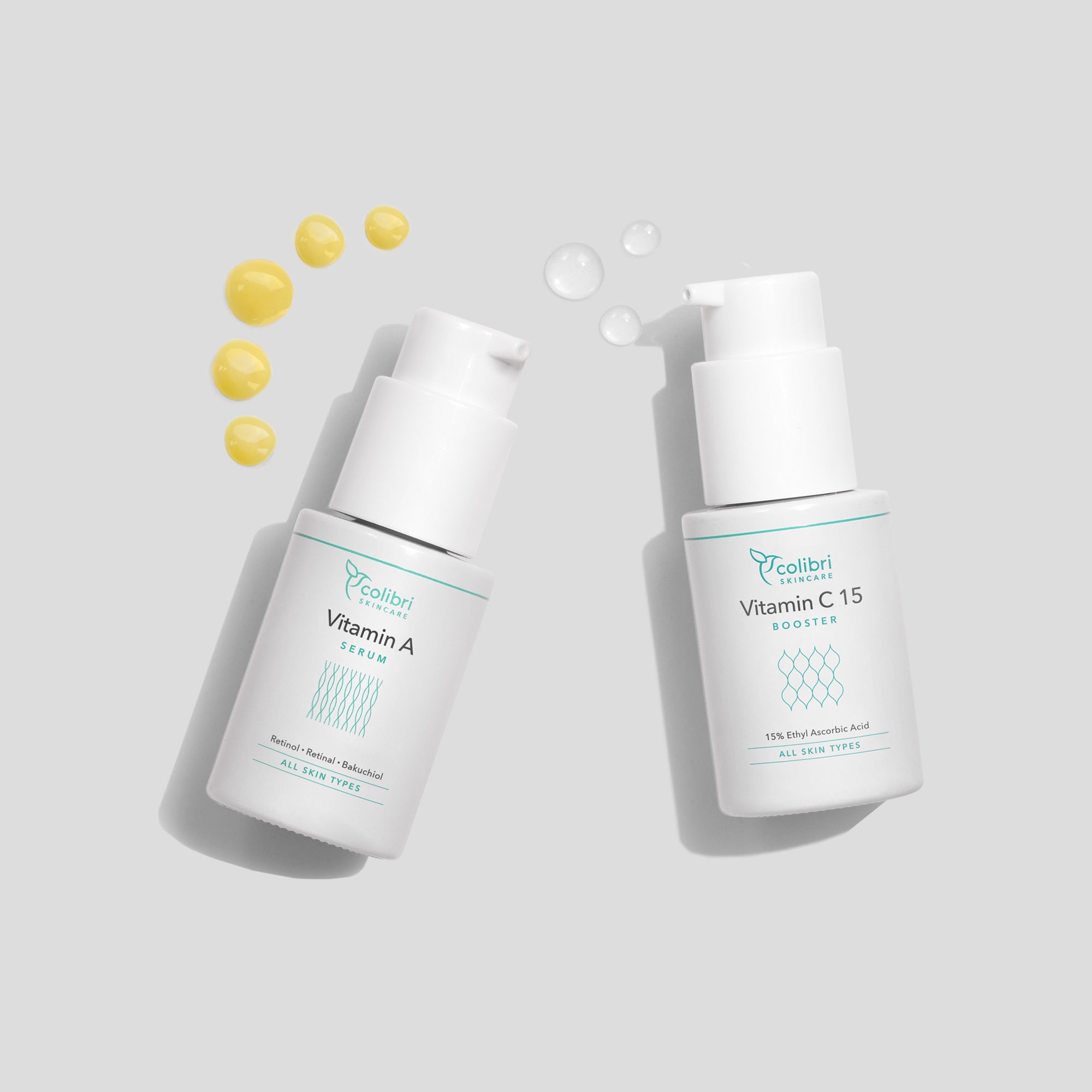 Zwei weiße Flaschen mit Vitamin A und Vitamin C Produkten, daneben gelbe und durchsichtige Flüssigkeitstropfen.