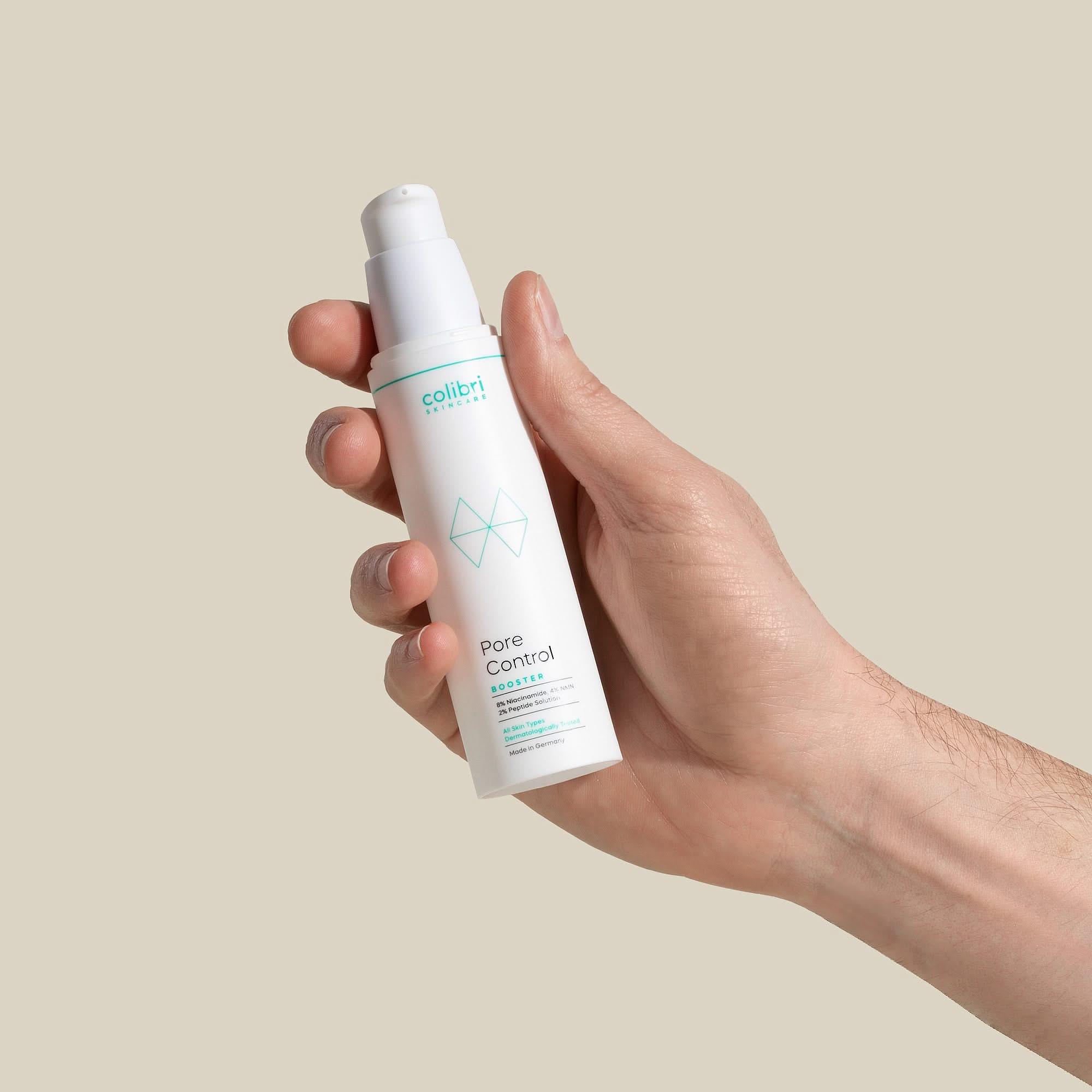 Hand hält eine weiße Flasche mit Kosmetikprodukt "Pore Control" von Colibri Skincare vor beigem Hintergrund.