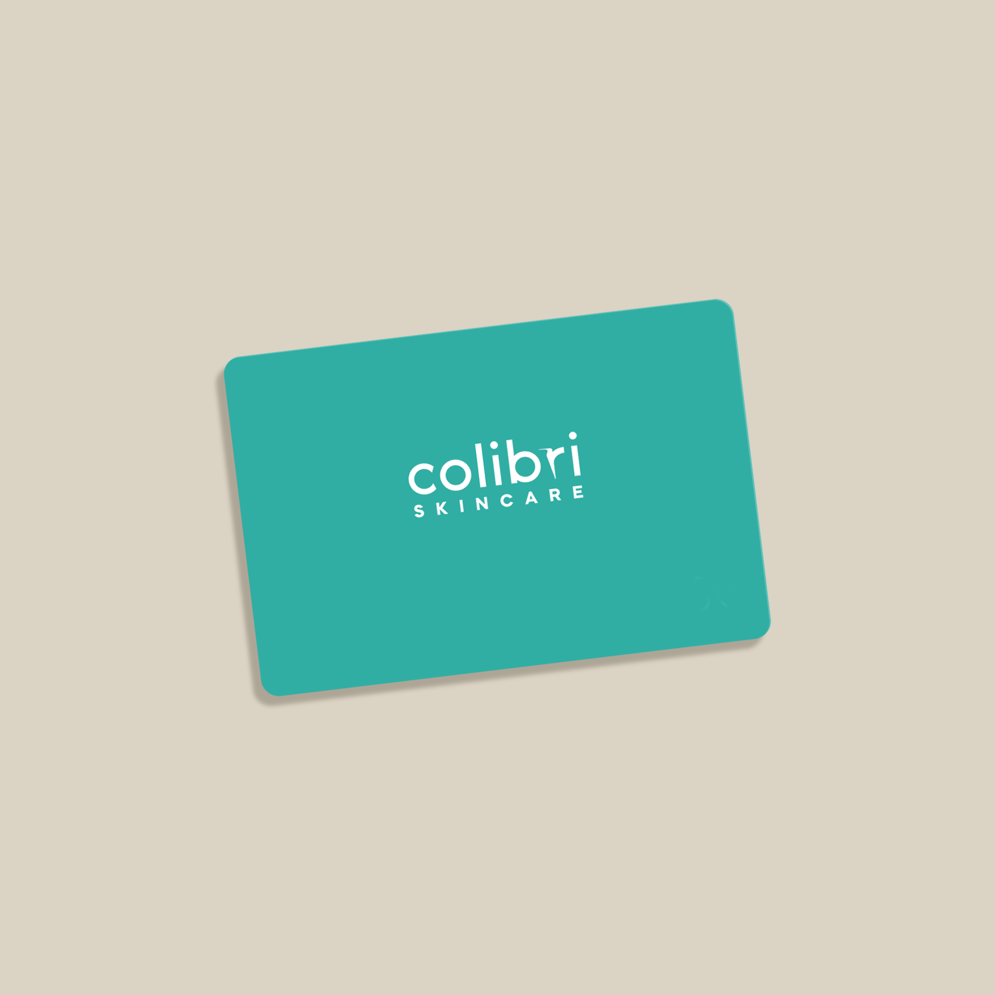Karte mit der Aufschrift "colibri SKINCARE" in Weiß auf einem türkisfarbenen Hintergrund, schräg auf beigefarbenem Untergrund.