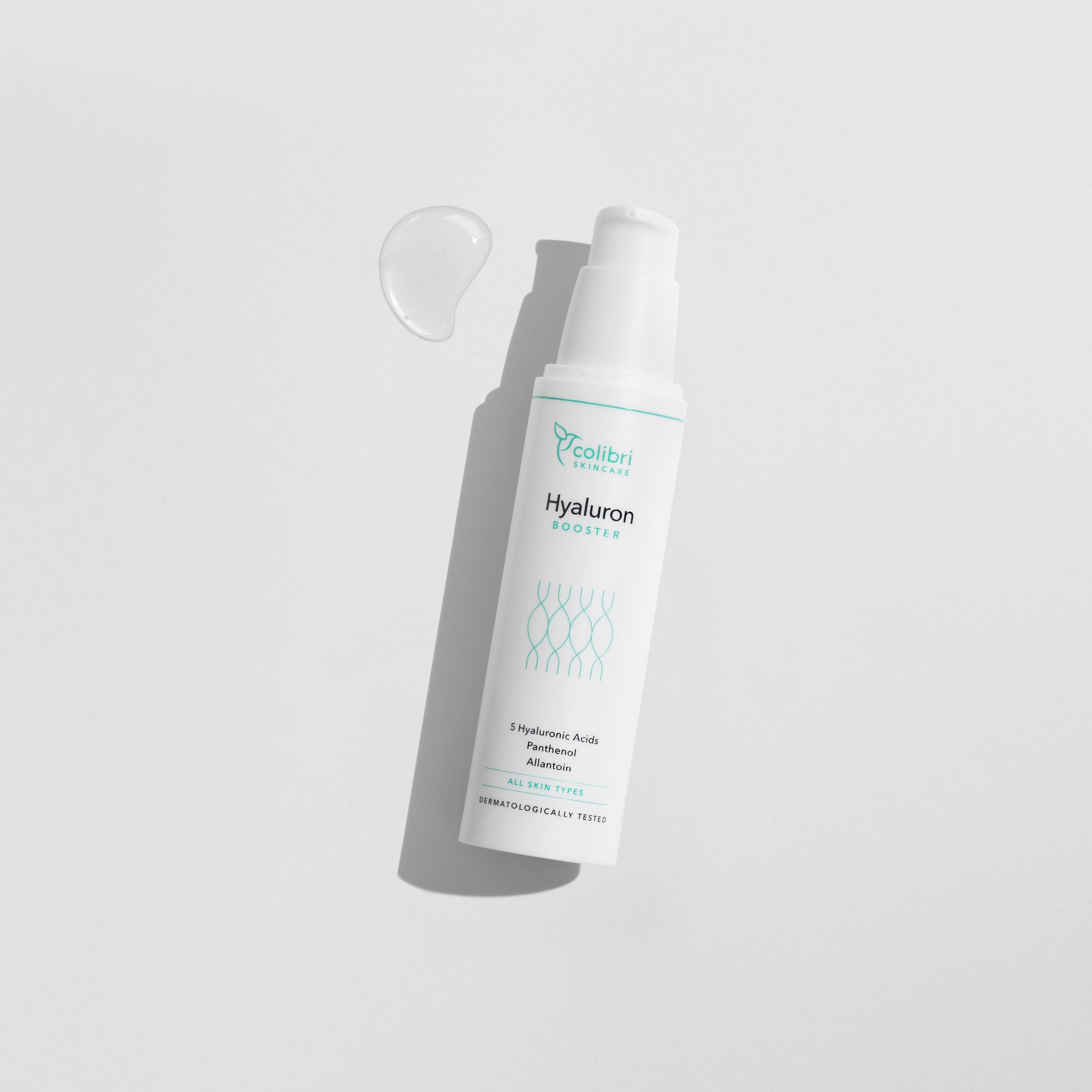 Weiße Flasche mit der Aufschrift "Hyaluron Booster" auf hellem Hintergrund mit einem Tropfen daneben.