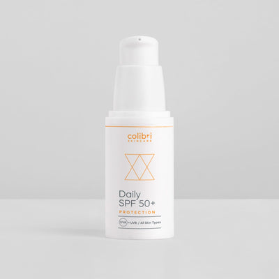 Weiße Flasche einer Sonnencreme mit der Aufschrift "Daily SPF 50+ Protection" auf grauem Hintergrund.