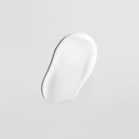 Weiße Lotion auf einer glatten, grauen Oberfläche ausgebreitet.